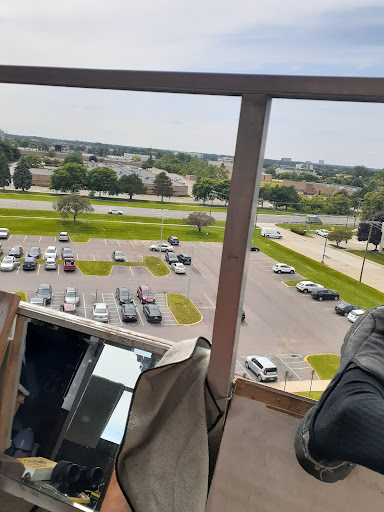 A view from a balcony overlooking a parking lot and surrounding landscape.