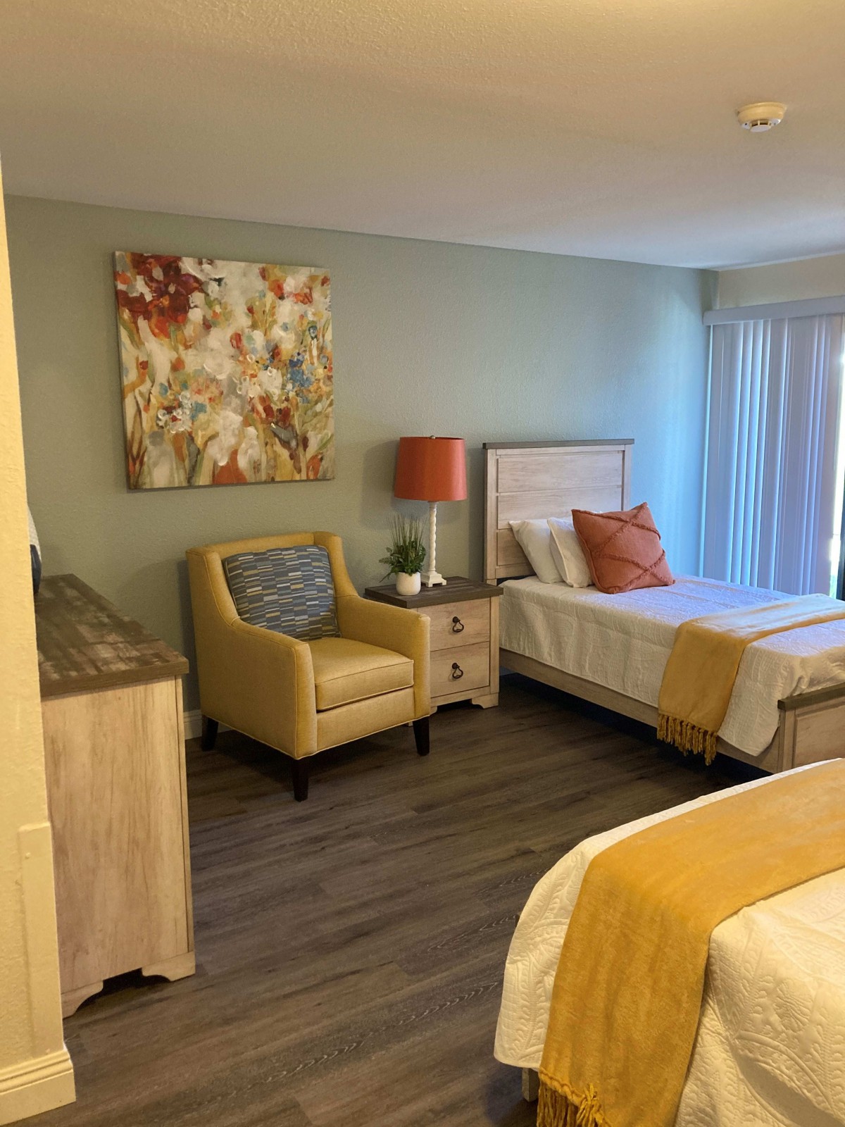 Cozy bedroom with a bed, armchair, and decorative artwork.