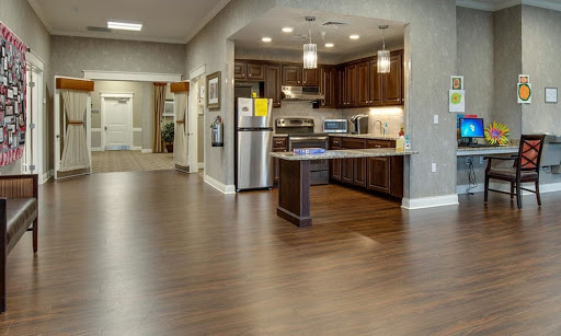 A modern kitchen with an open layout, featuring dark wood cabinetry and sleek appliances.