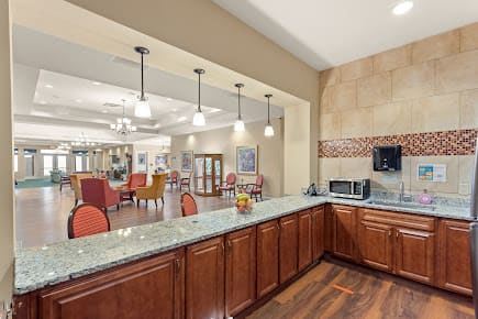 A spacious kitchen area with a granite countertop and view of the dining area.