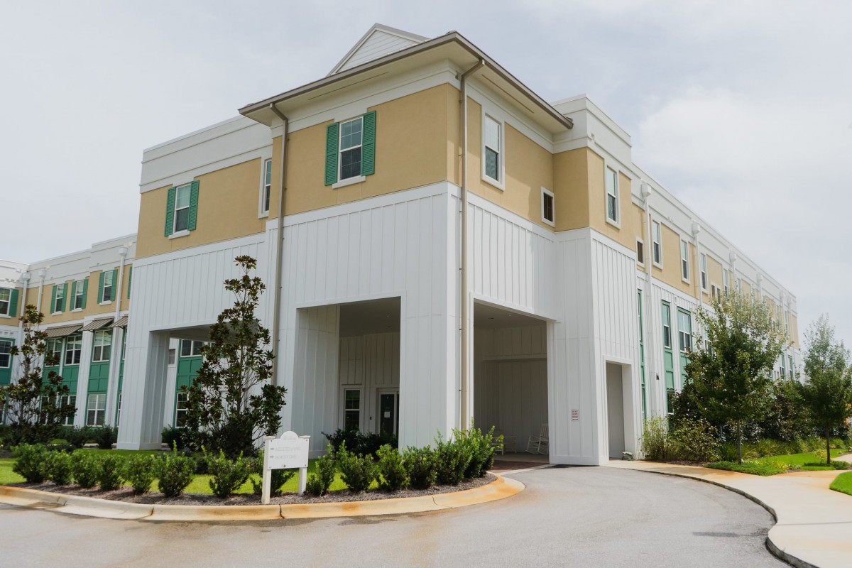 A modern residential building with a driveway and landscaping.