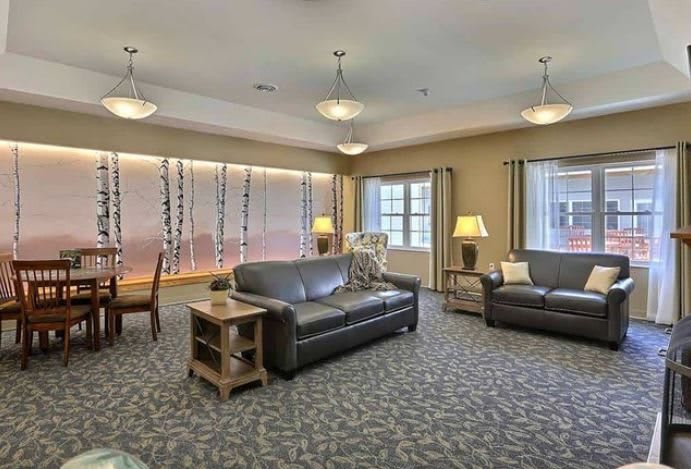 A spacious and well-lit living room with sofas, lamps, and large windows.