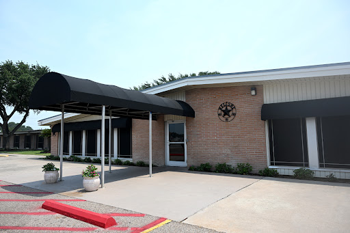 An exterior view of a commercial building featuring a covered entrance and parking area.