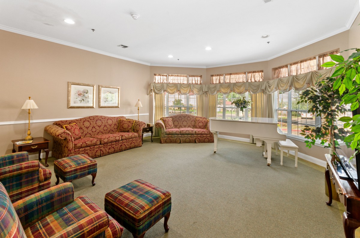 A cozy living room with comfortable seating, a piano, and large windows that let in natural light.