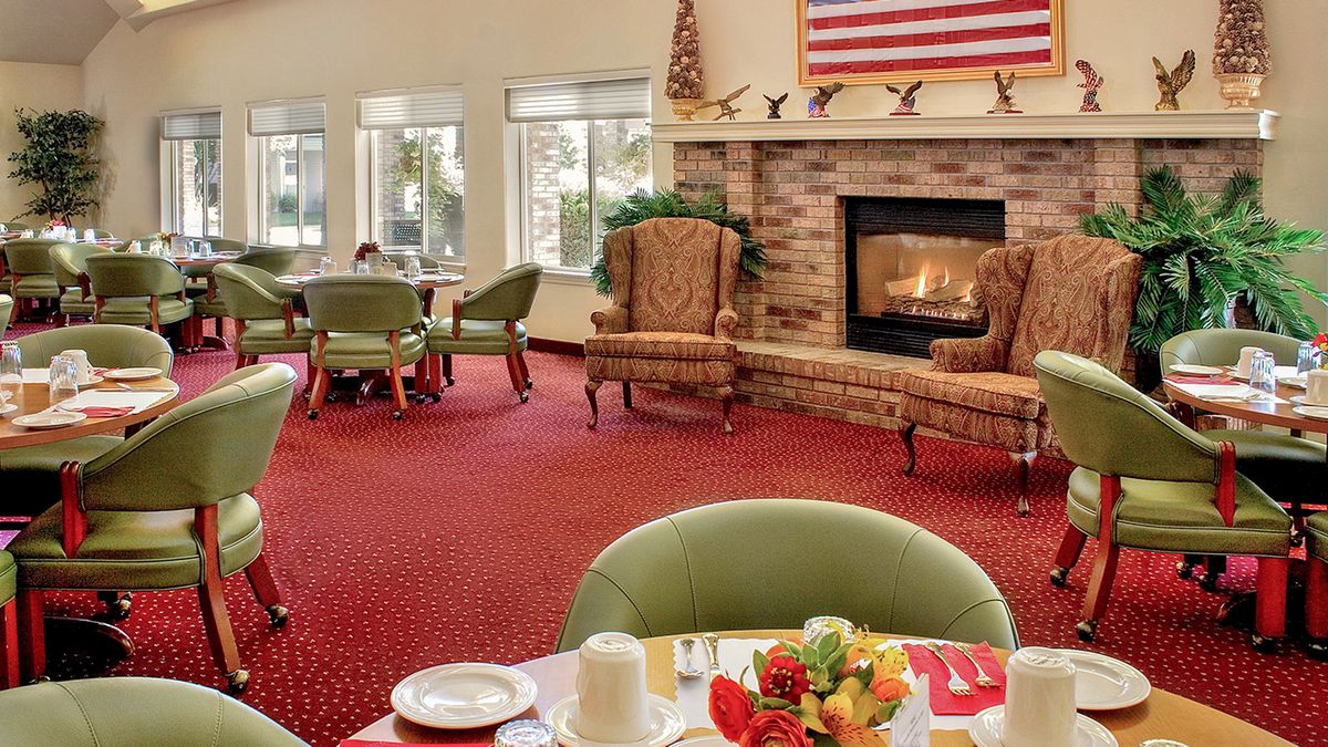 A cozy dining area with a fireplace, featuring chairs and tables on a red carpet.