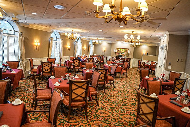 An elegantly set dining room with chandeliers and neatly arranged tables and chairs.