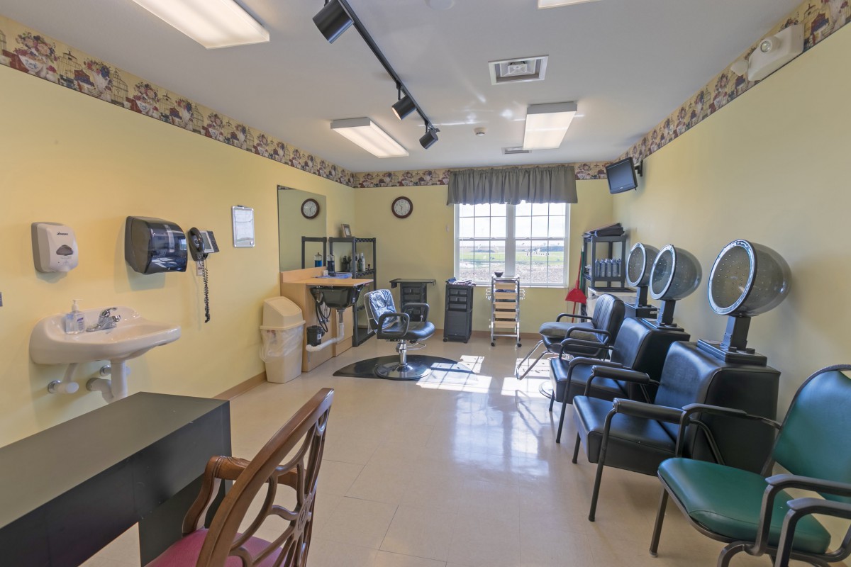 A well-lit salon with a waiting area, chairs, mirrors, and hair dryers.