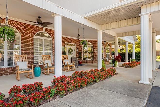 A charming porch with rocking chairs and vibrant flowers lining the path.