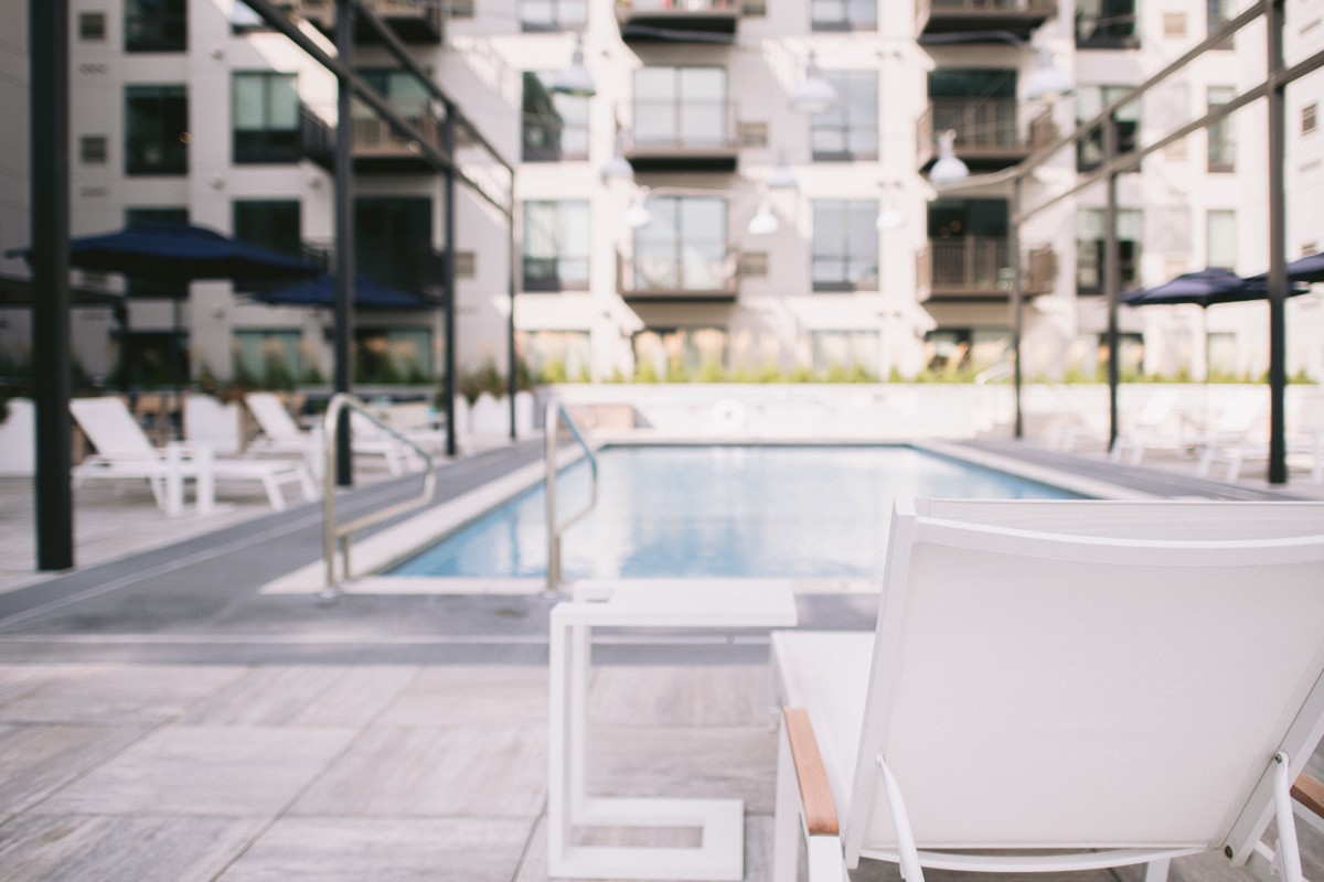 A modern apartment complex with a swimming pool and outdoor seating area.