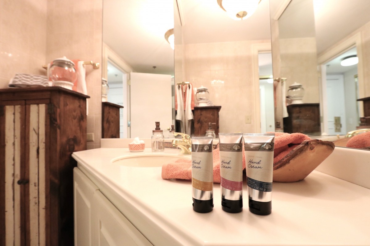 A clean bathroom countertop with toiletries and towels neatly arranged near a mirror.