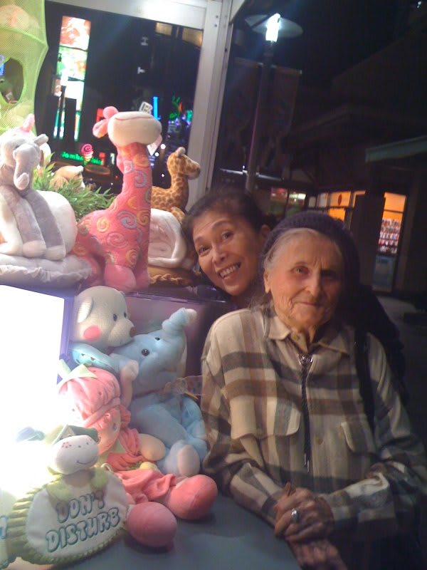 Two people smiling with a display of stuffed animals.