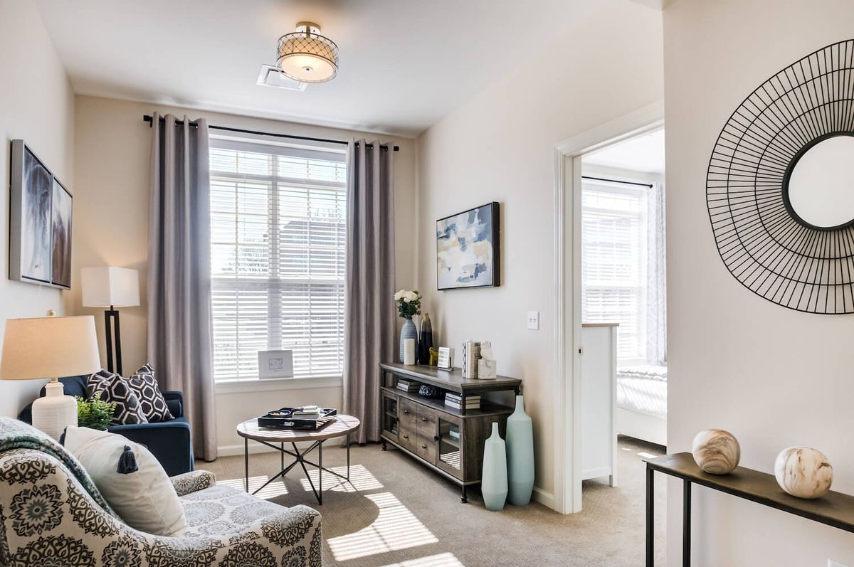 A modern living room with ample natural light, featuring stylish furniture and decor elements.