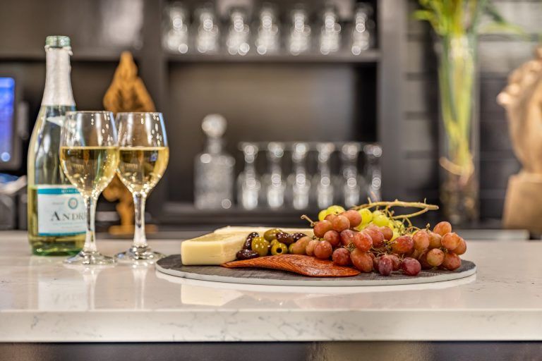 A sophisticated setting featuring wine glasses and a platter of cheese and grapes.