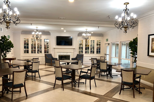 A spacious dining area featuring tables, chairs, and elegant chandeliers.
