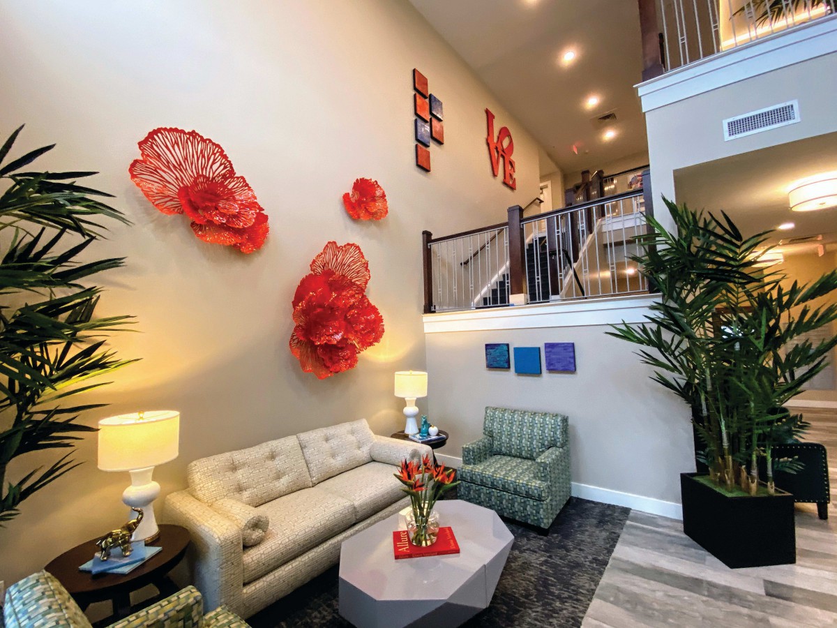 A modern living room with vibrant red wall art, stylish furniture, and indoor plants.