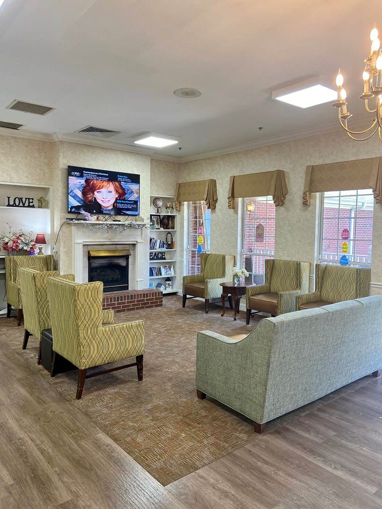 A cozy lounge with comfortable seating and a television above the fireplace.