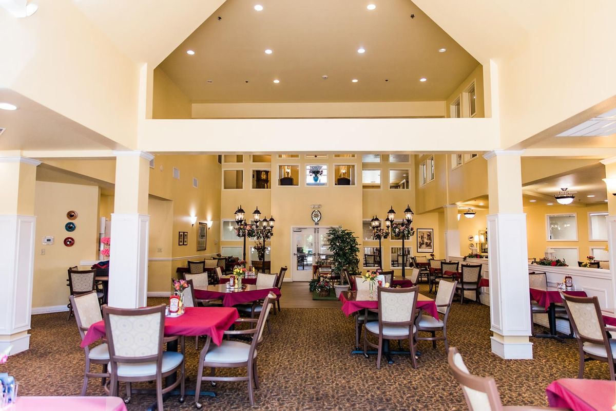 A spacious dining room with neatly arranged tables and chairs, warm lighting, and tasteful decor.