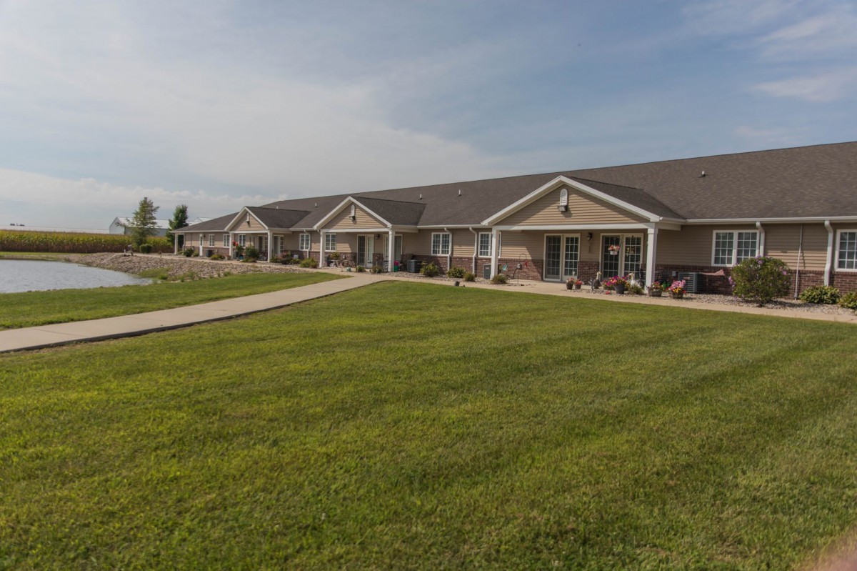 A row of residential buildings with a well-maintained lawn and pathway under a clear sky.