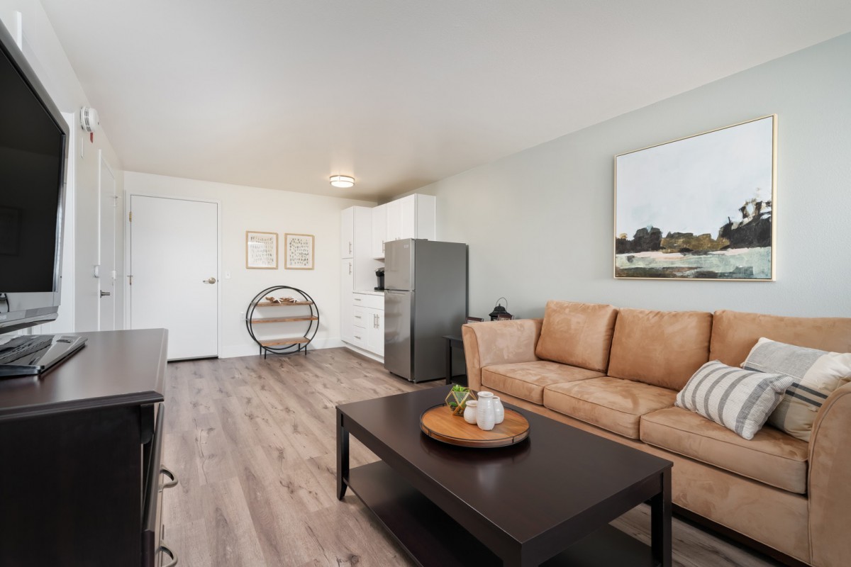 A modern living room with a tan sofa, wooden coffee table, and minimalist decor.