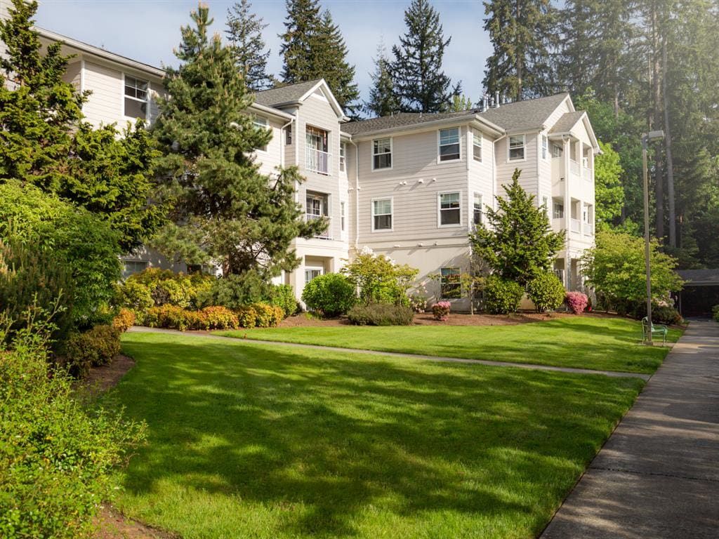 A well-maintained apartment building surrounded by lush greenery and trees.
