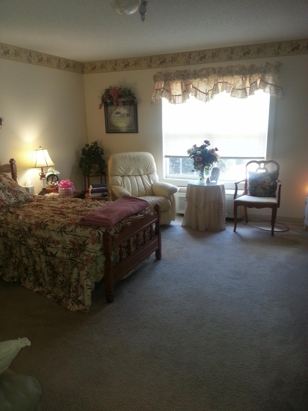 A cozy bedroom with a bed, armchair, and window with natural light.