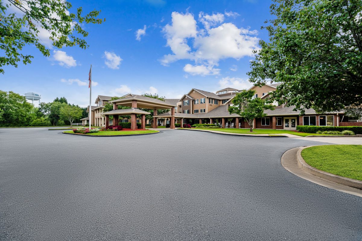 A wide-angle view of a large building complex with a circular driveway under a blue sky.