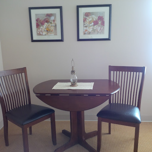 A cozy dining setup featuring a round table and two chairs, complemented by framed art on the walls.
