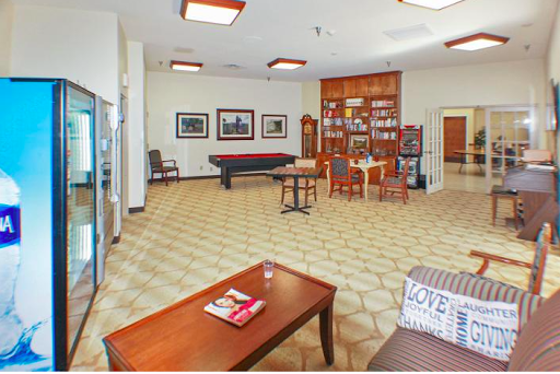 A cozy lounge area featuring comfortable seating, a bookshelf, and recreational amenities.