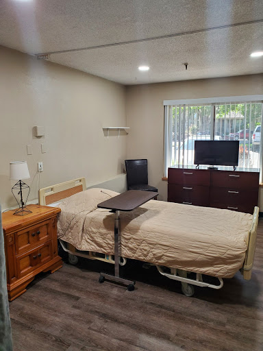 A well-equipped hospital room featuring a patient bed, a television, and a wooden dresser.