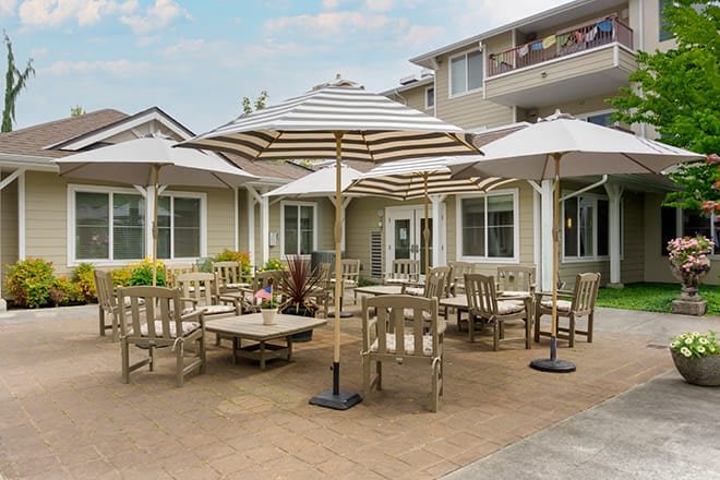 A residential outdoor patio area with tables, chairs, and umbrellas.