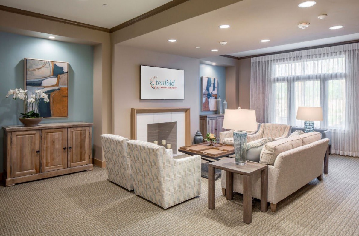 A cozy and elegantly decorated living room with a fireplace, comfortable seating, and tasteful artwork.