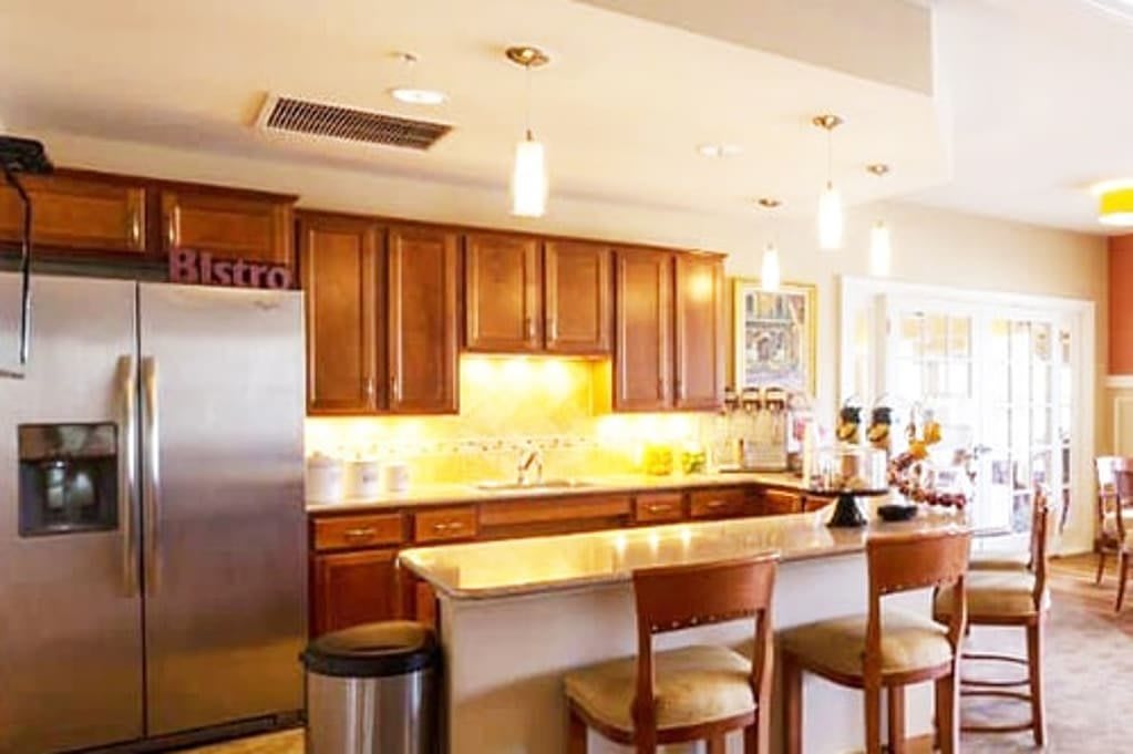 A modern kitchen with wooden cabinets, a marble counter, and bar stools.