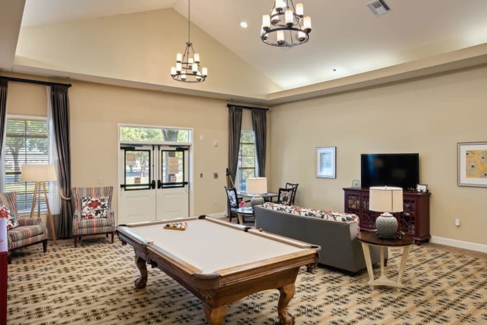 Spacious living area with a pool table, comfortable seating, and modern chandeliers.