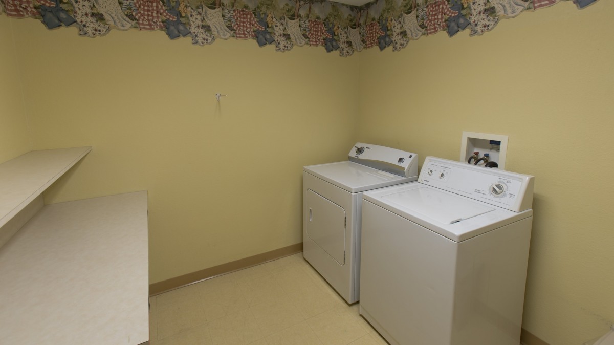 A laundry room featuring a washing machine and dryer against a yellow wall.