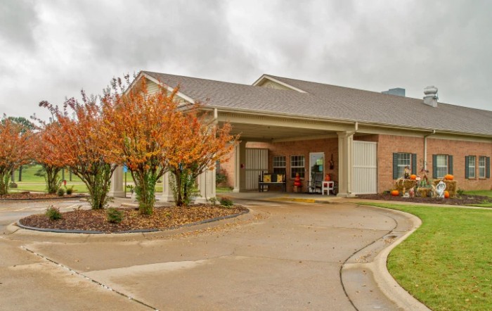 A building entrance surrounded by autumn trees and a cloudy sky.