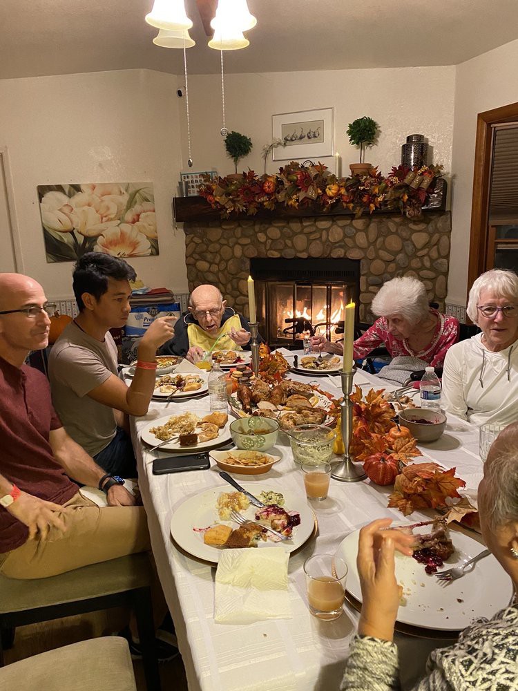 A family enjoying a festive dinner together by the fireplace with autumn decorations.