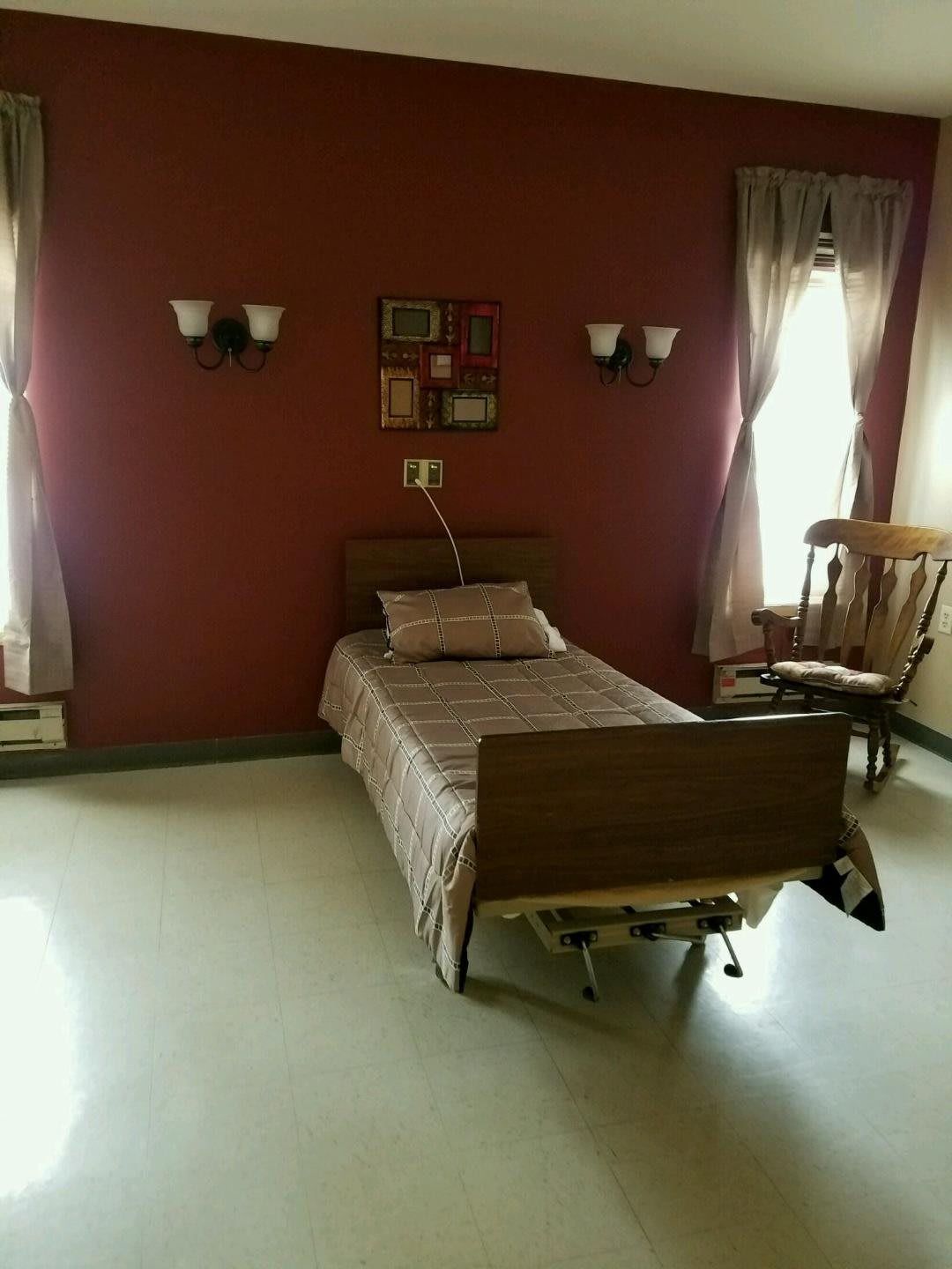 A simple room with a hospital bed and wooden furniture.