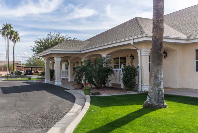 A well-maintained residential house with a manicured lawn and palm tree.