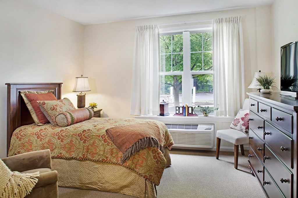 Cozy bedroom with a bed, lamp, and window view.