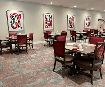 A modern dining area featuring several tables and chairs, decorated with abstract artwork on the walls.