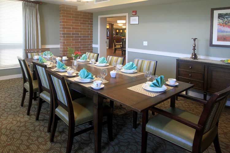 A well-set dining table in a formal dining room with neatly arranged chairs and turquoise napkins.