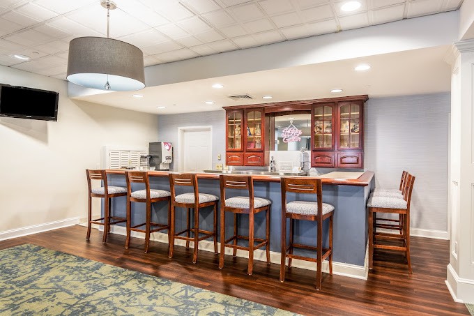A cozy home bar area with wooden stools and modern lighting.