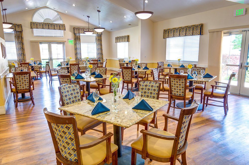 A well-arranged dining room with tables set for a meal, featuring chairs and decorative table settings.