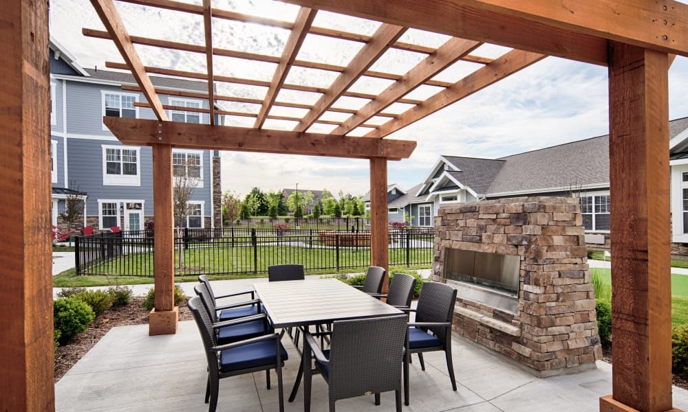An inviting backyard patio with a pergola, featuring an outdoor dining area and a stone fireplace.