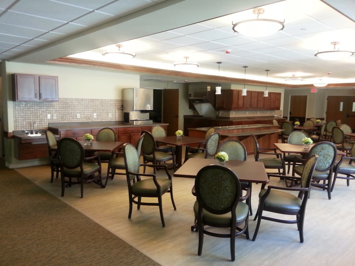 An empty dining area with several tables and chairs, featuring a bar in the background.