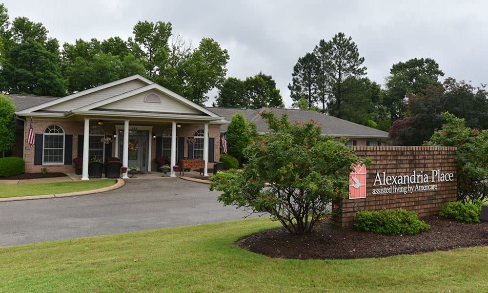 A charming building entrance surrounded by well-maintained landscaping and a sign at the front.
