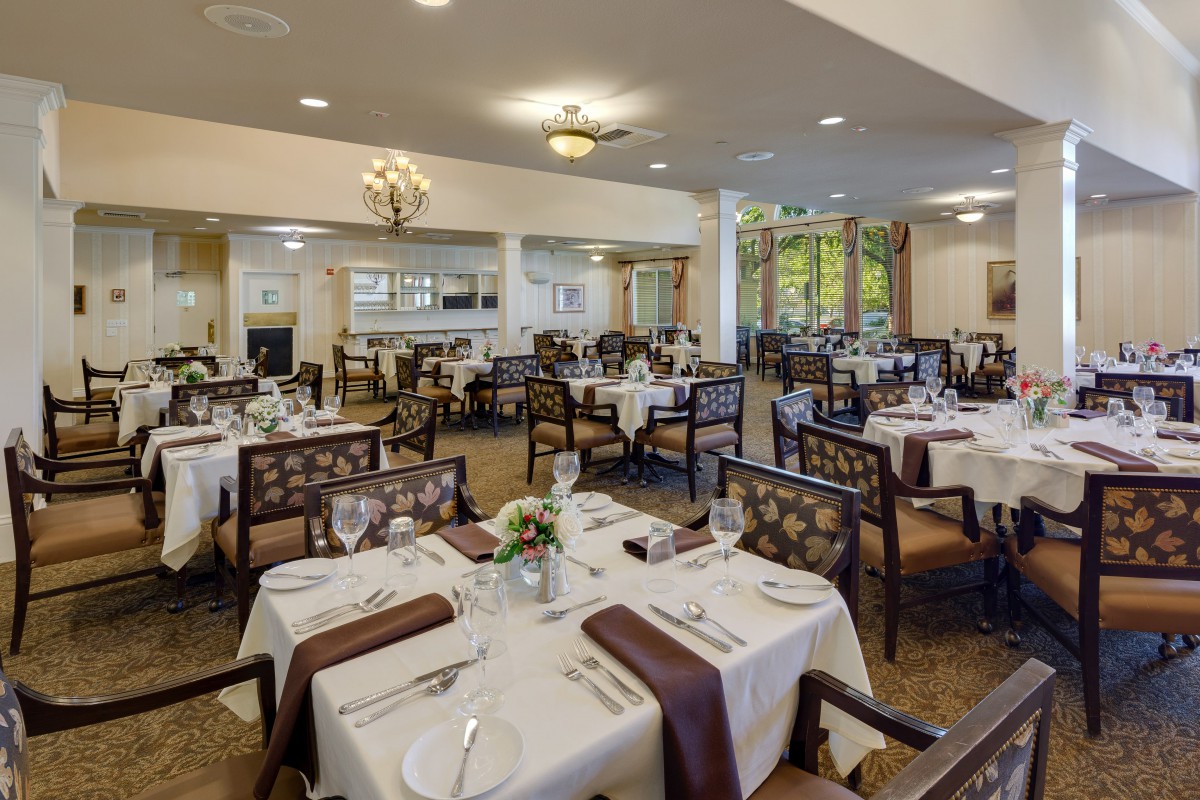 An elegantly set dining room with neatly arranged tables and chairs, ready for guests.