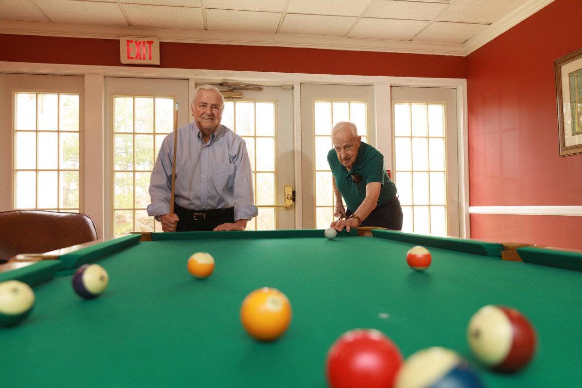 Two men enjoying a game of billiards in a game room.