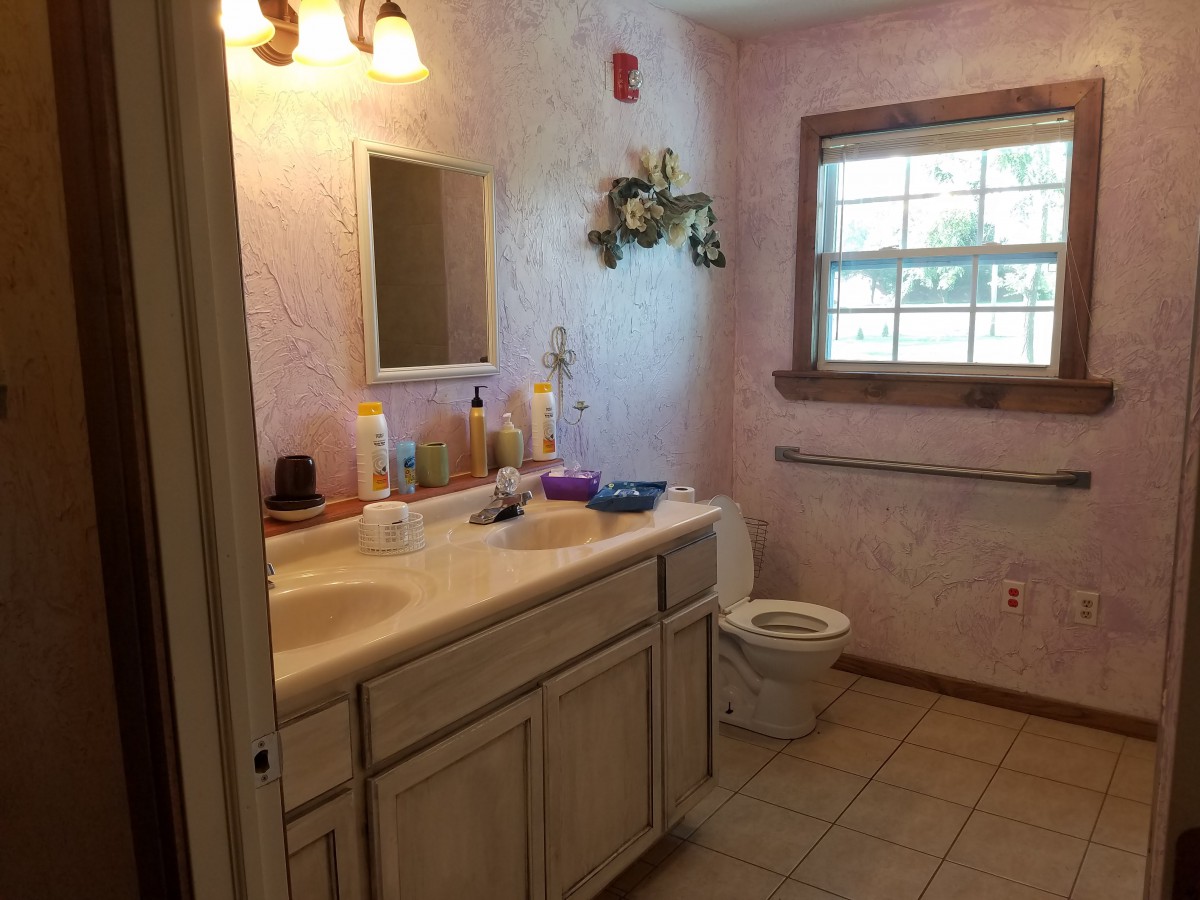 A cozy bathroom with a sink, mirror, and toilet, featuring decorative elements and natural lighting.