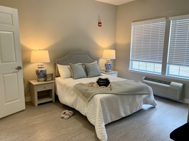 A cozy bedroom with a neatly made bed, flanked by two nightstands with lamps.